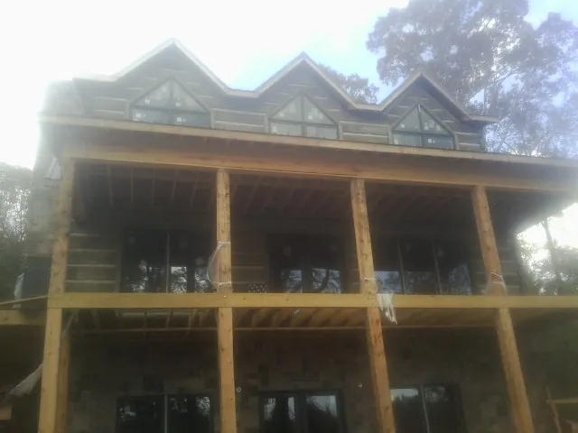 Dormers and porch framing on a large log home under construction — Roof Coating work by our crew in Bellevue