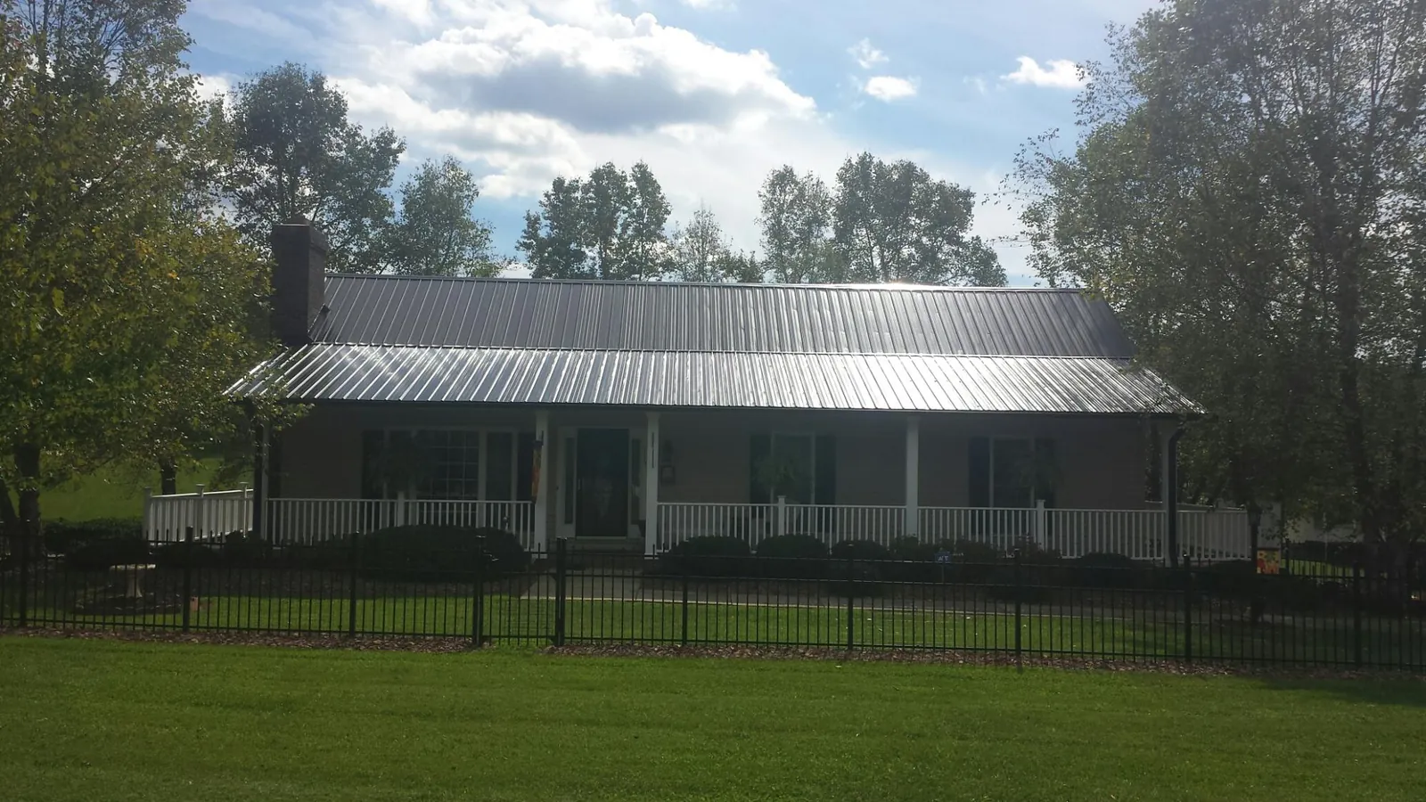 Gray metal roof on a brick ranch with a full width front porch — Gutter Guard Installation work by our crew in Bellevue